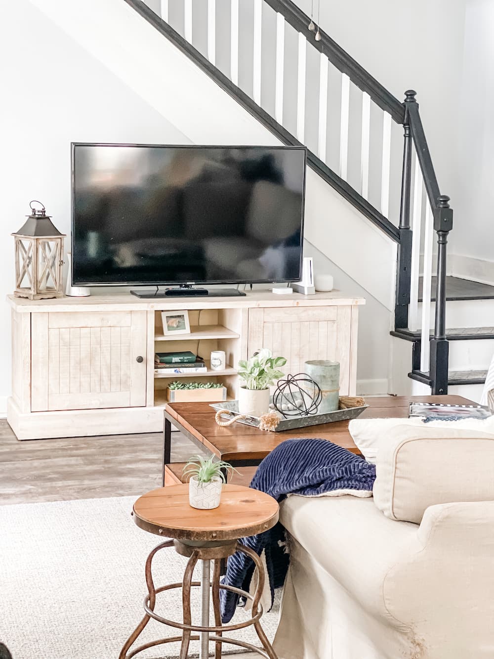 tv on stand in front of black and white steps and view of coffee table