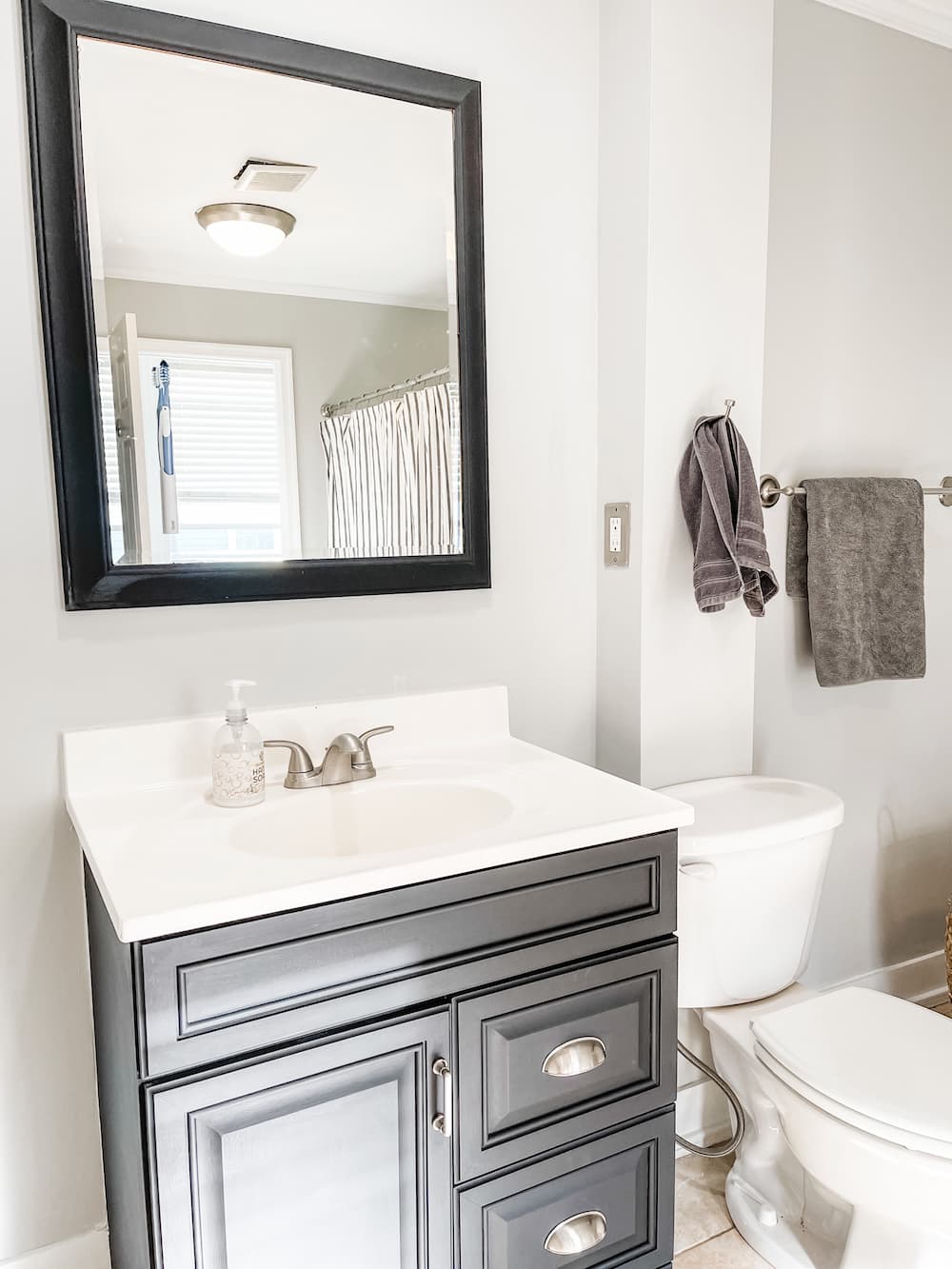 grey bathroom with black vanity and mirror