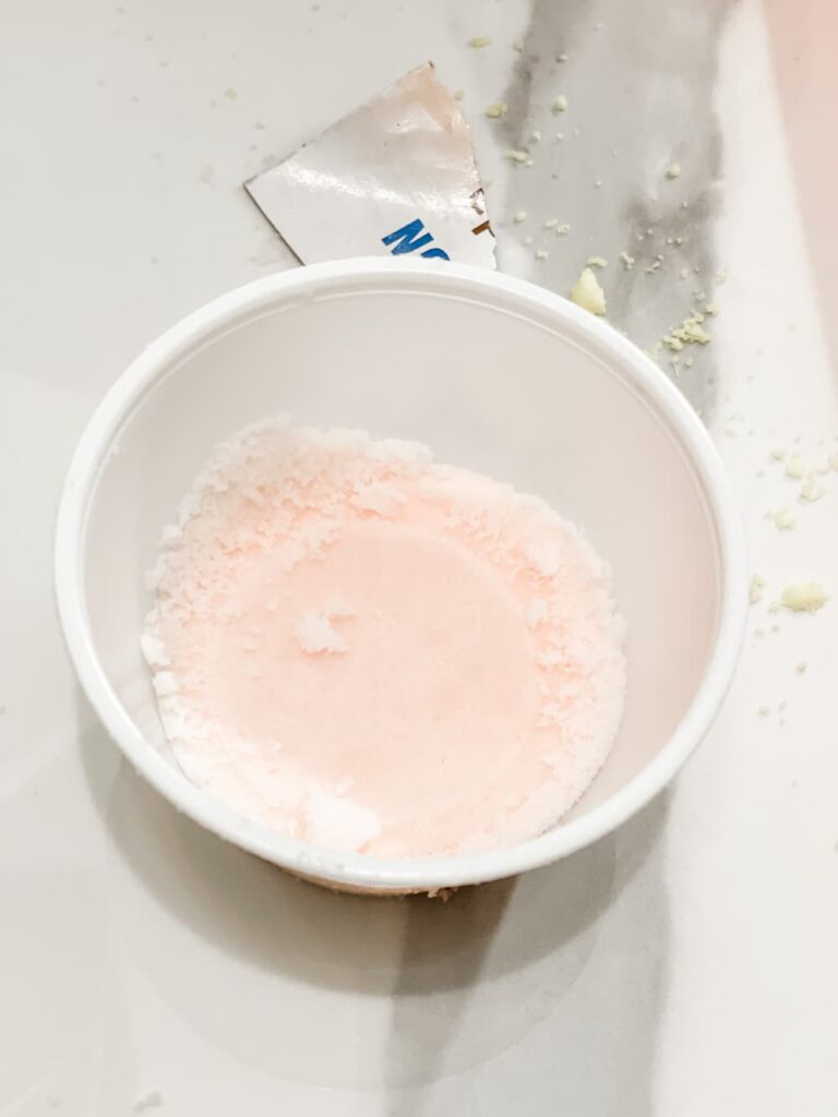 small plastic container holding a diy shower melt in pink