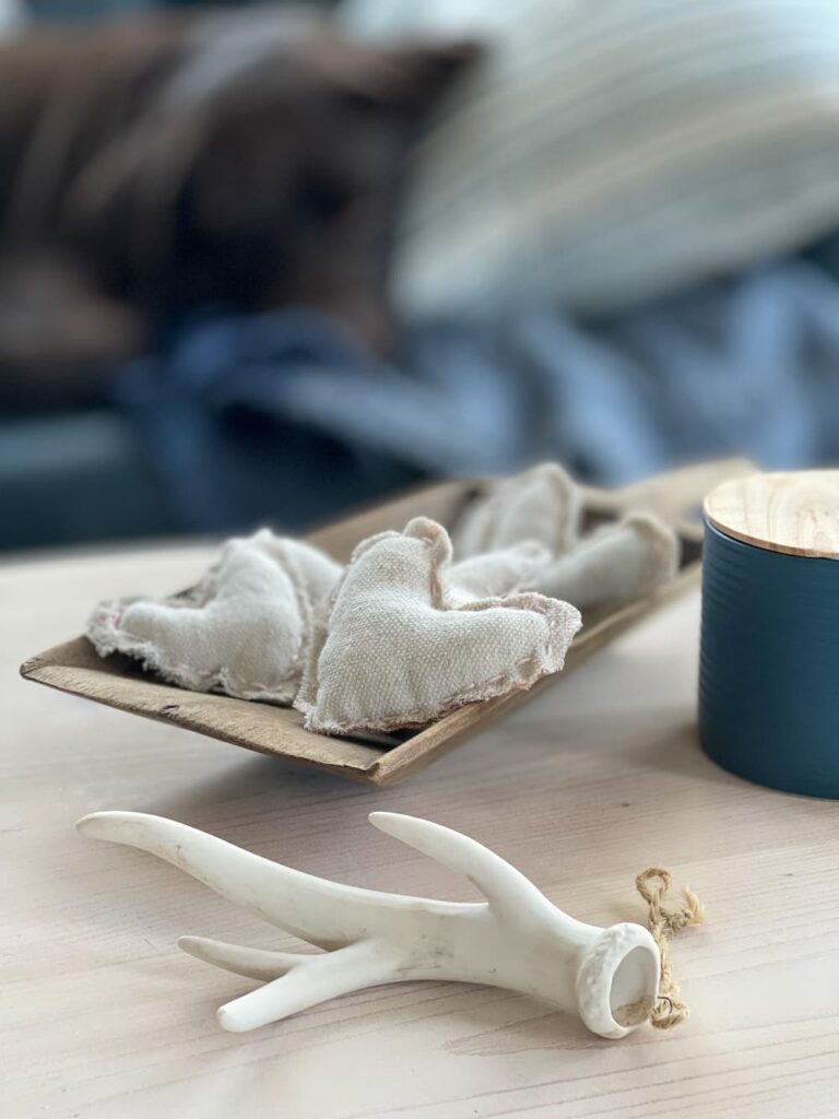 A WOODEN DOUGH BOWL WITH 5 RUSTIC CLOTH VALENTINE HEARTS STITCHED IN PINK