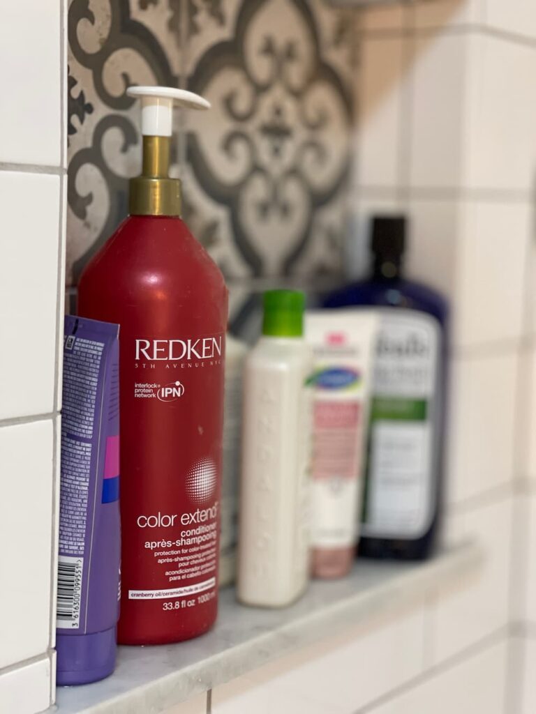 mismatched bottles of shampoo and conditioner on shelf in shower