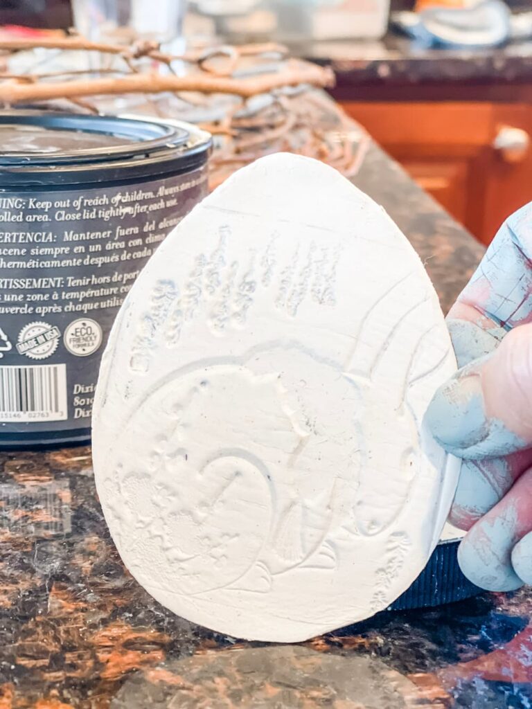 WHITE STAMPED CLAY EGG GETTING READY TO BE PAINTED
