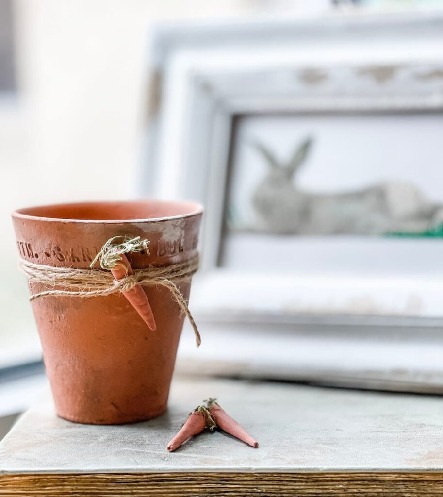 small clay pot with a clay carrot attached with twine to the top