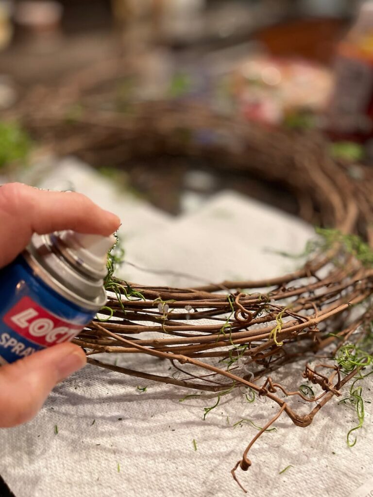 spraying grapevine wreath with spray adhesive