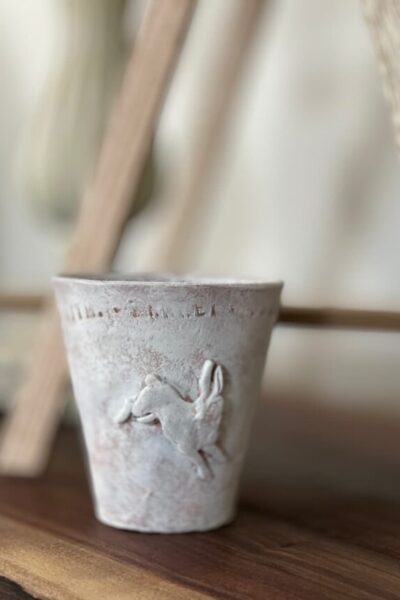 clay pot whitewashed with a small clay bunny on the outside.