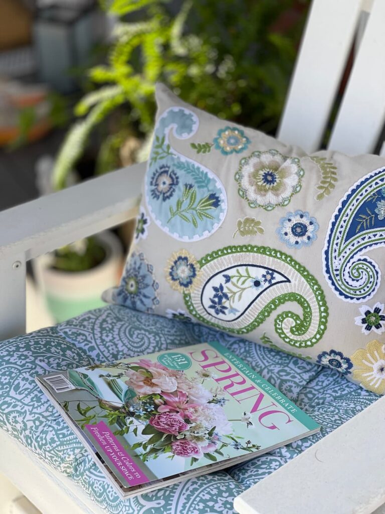 a white chair with a pillow and cushion and a copy of a spring magazine