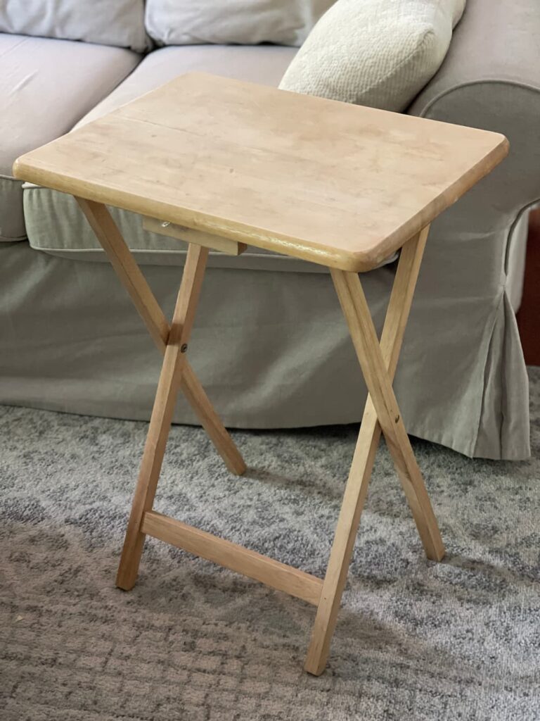 an old wooden tv tray set up in front of a sofa