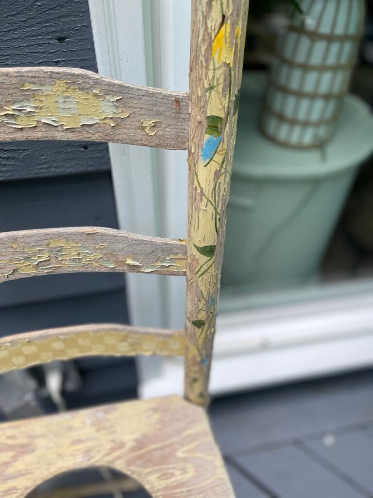 A CLOSE UP OF A WOODEN CHAIR PLANTER ALL CHIPPED