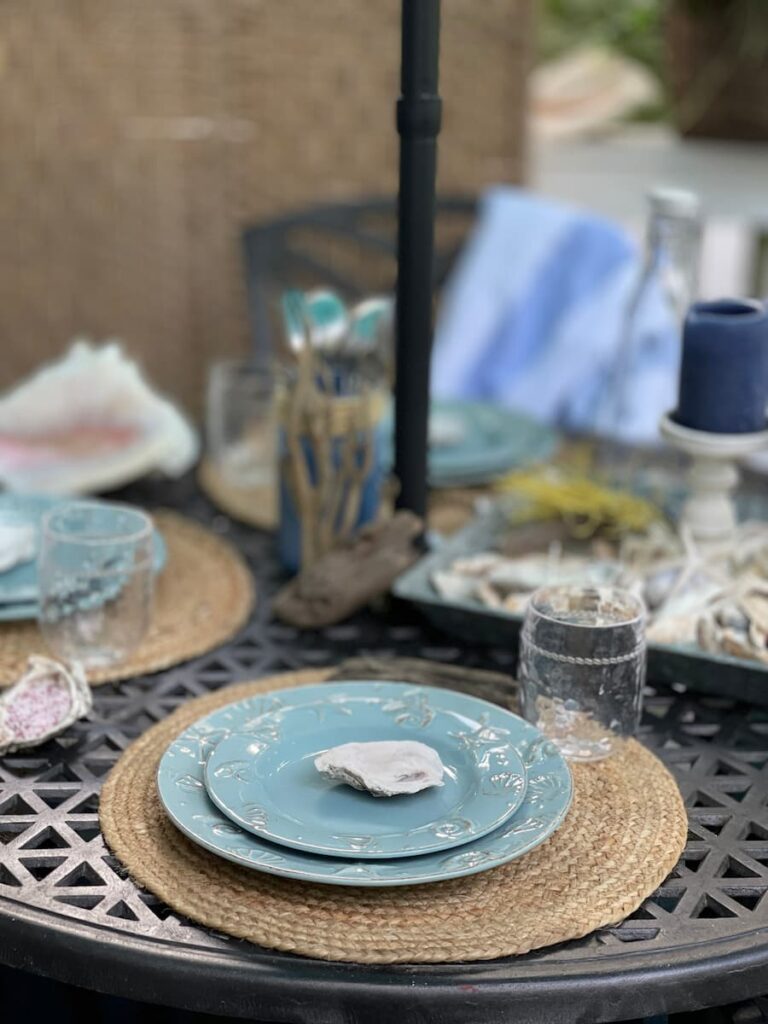A PLACE SETTING WITH SHELL DISHES ON A ROUND JUTE PLACEMAT