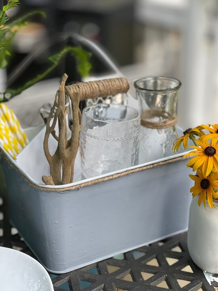 A light blue silverware caddy with rope trim and twine wrapped handle.